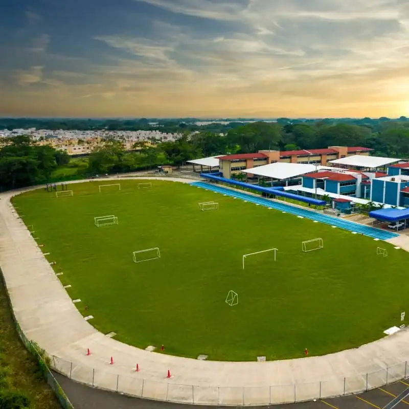Complejo deportivo con cancha de fútbol de pasto sintético verde, equipamiento moderno y vista aérea de Villahermosa