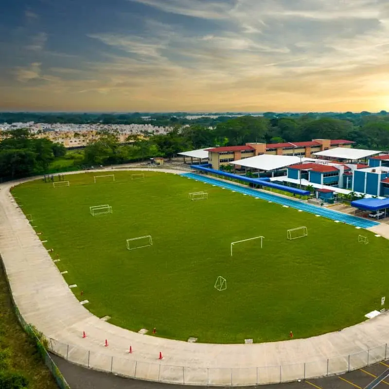 Complejo deportivo con cancha de fútbol de pasto sintético verde, equipamiento moderno y vista aérea de Villahermosa